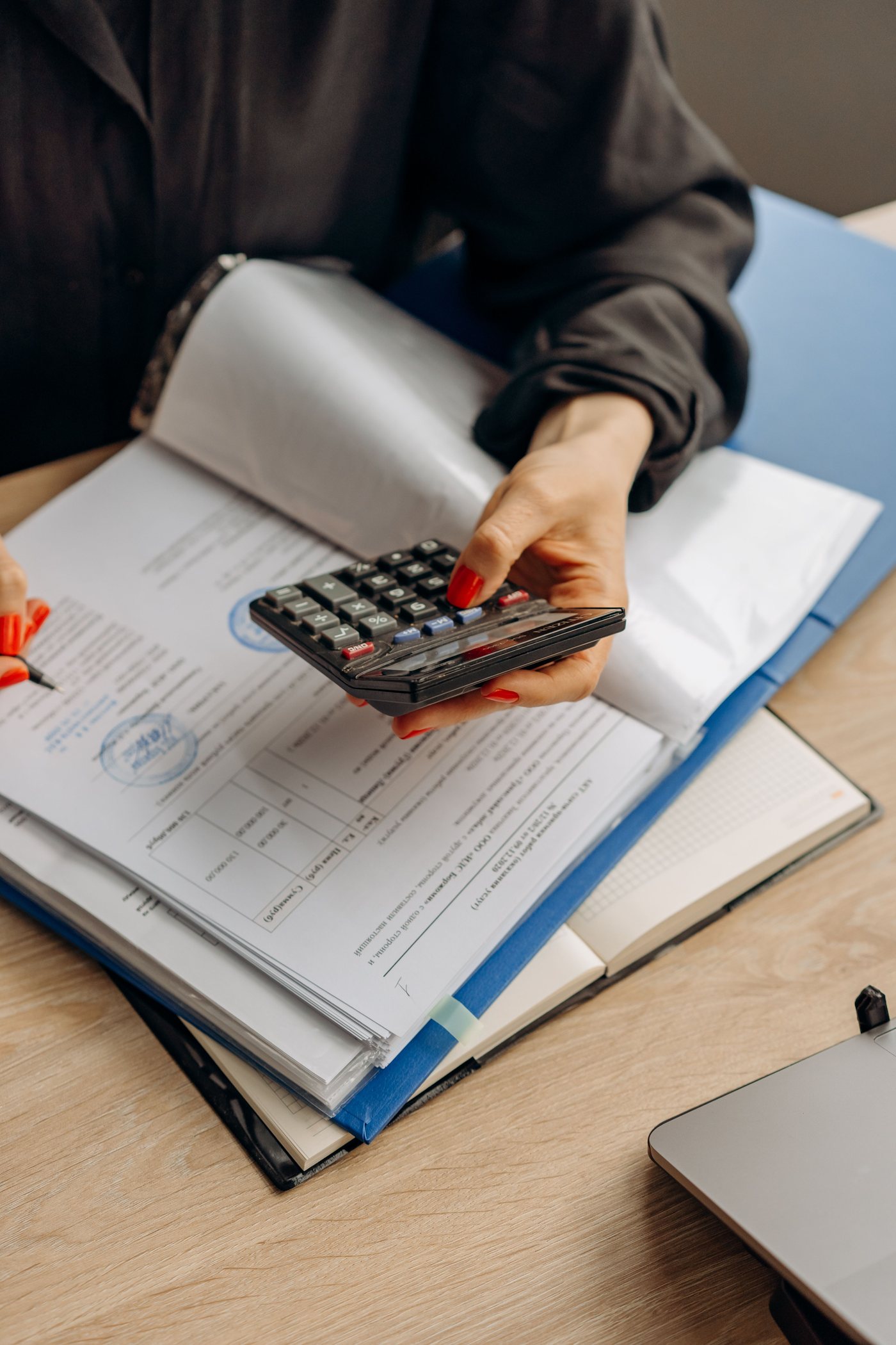 Profissional analisando calculadora, planilhas e documentos contábeis